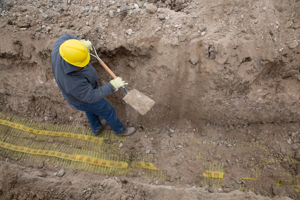 Handwerker hebt einen Graben für eine Drainage aus