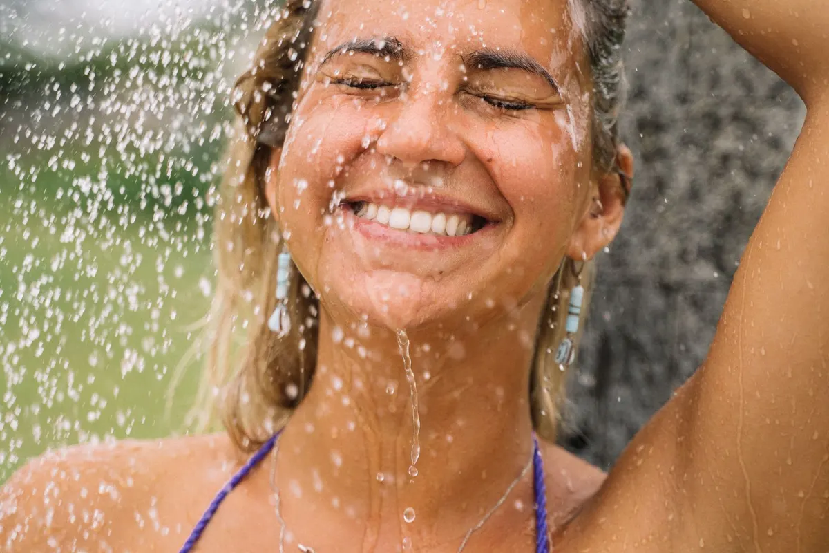 Person erfrischt sich unter einer Gartendusche