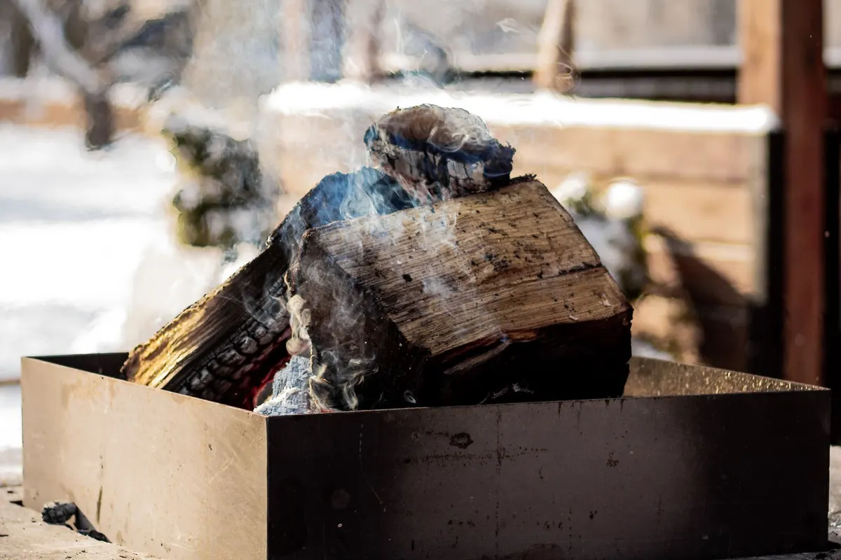 Brennendes Holzscheit in einem gemauerten Gartenkamin