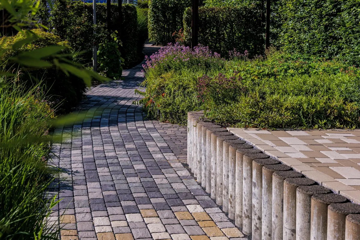 Gepflasterter Gartenweg mit Bepflanzung und Bank