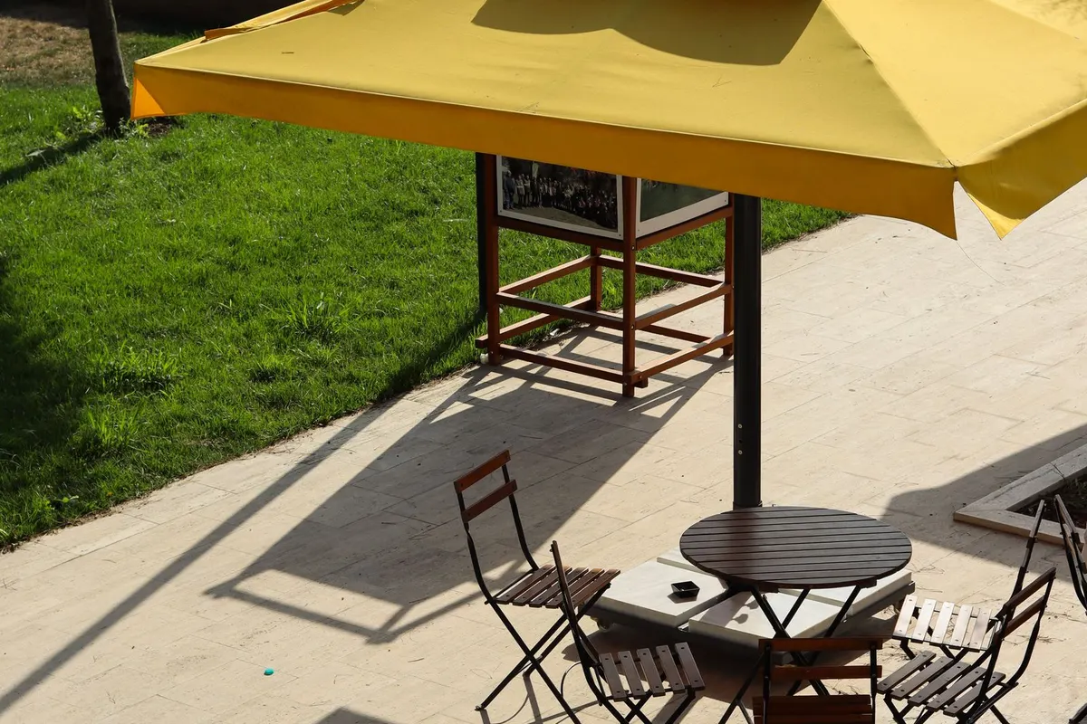 Gelber Sonnenschirm über einem Bistrotisch auf der Terrasse