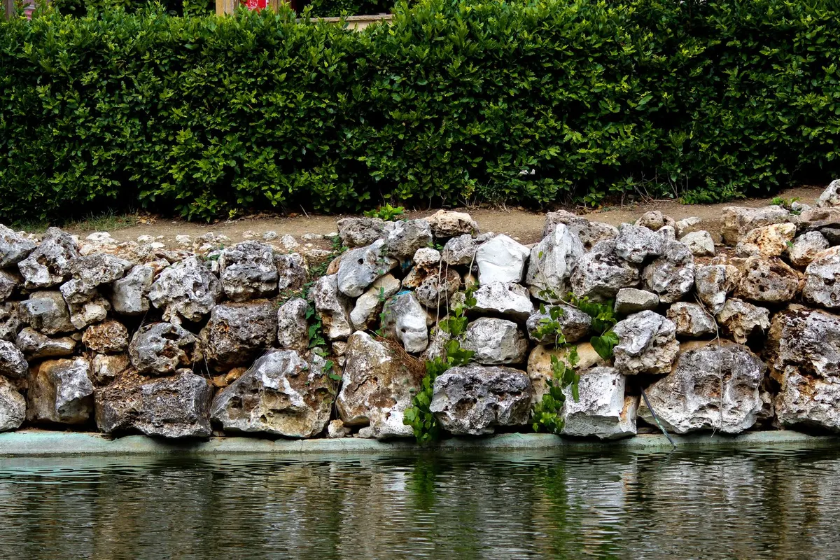 Steinerne Stützmauer entlang eines Hangs am Wasser