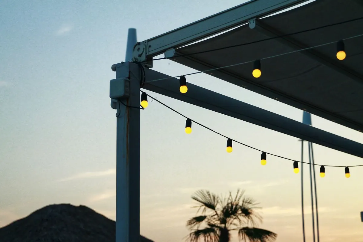 Moderne Terrassenüberdachung mit Lichterkette gegen den Abendhimmel